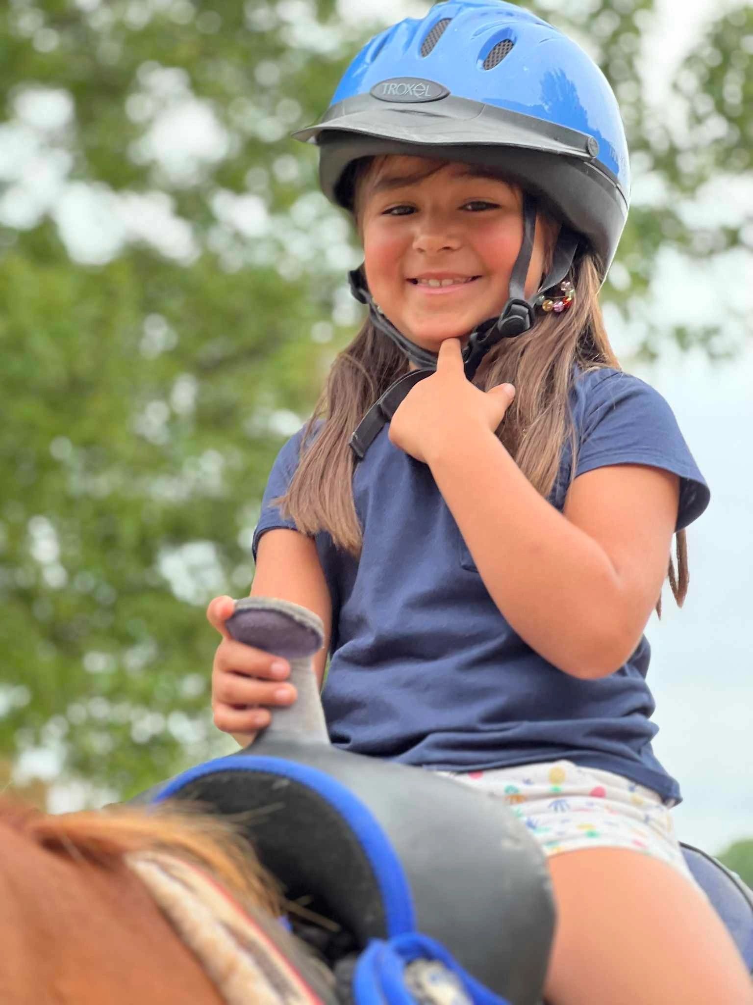 Child with riding helmet giving thumbs up